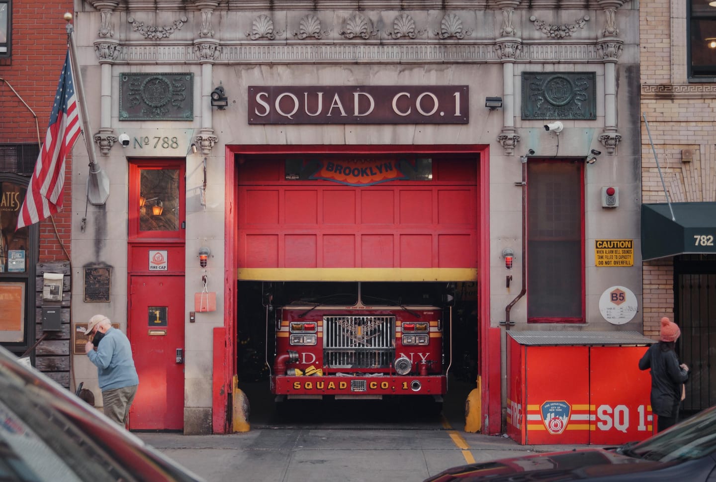 A red fire station marked Squad Co. 1 with a fire engine parked in the open bay.
