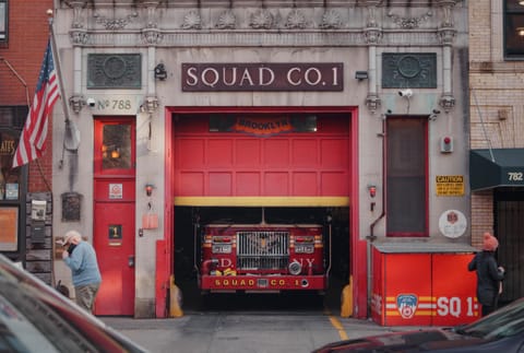 A red fire station marked Squad Co. 1 with a fire engine parked in the open bay.