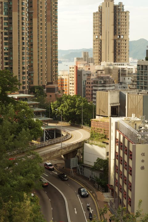 An elevated road curving between high-rise apartment towers, the sea visible in the distance.