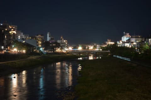 A river running through a city at night, lit buildings and a bridge reflected in the water.